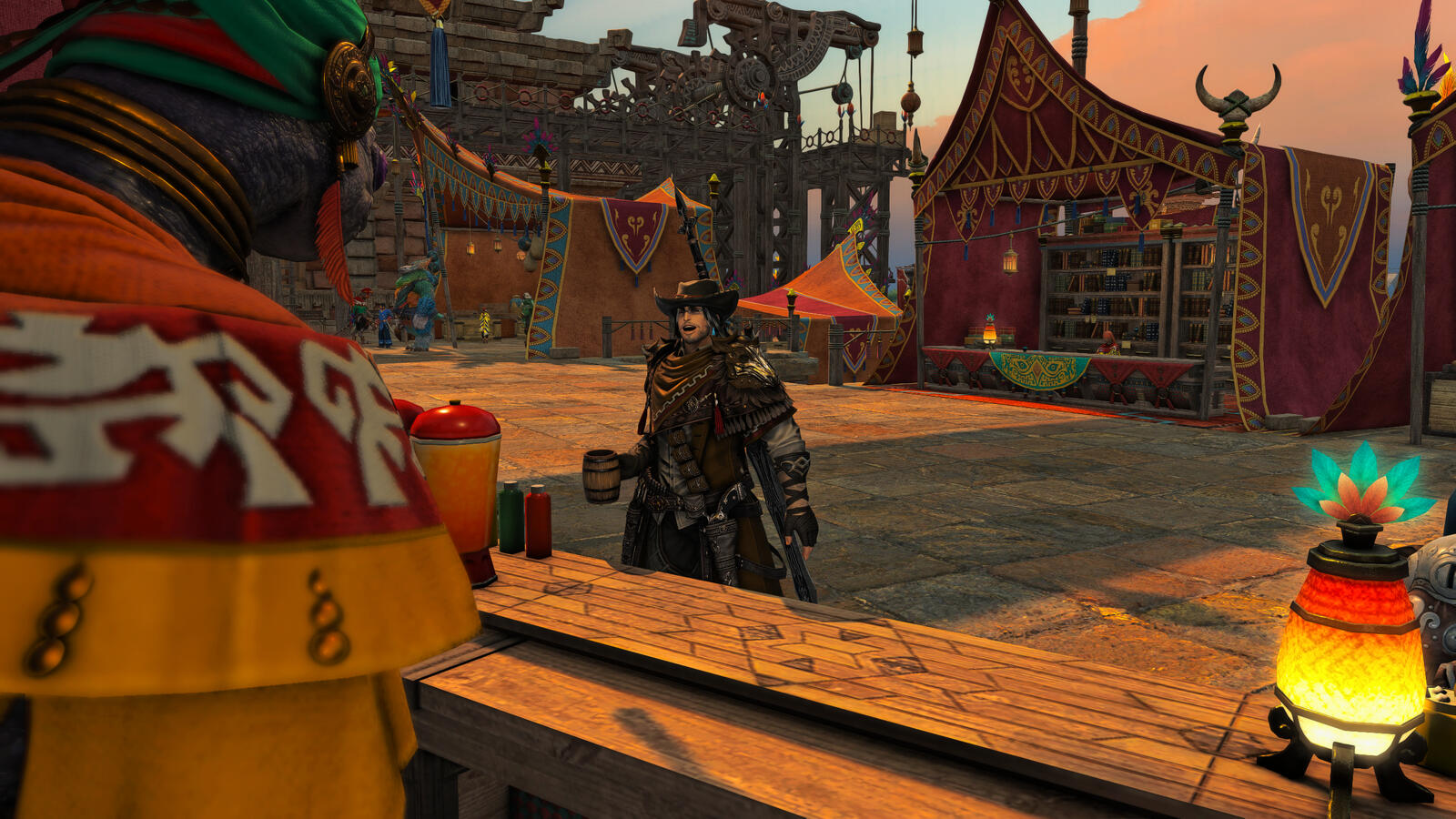 Erston stands at a market stall in the Wachumeqimeqi markets at dawn, dressed in brown armor and a wide-brimmed hat. He holds a mug while speaking to a robed merchant amid colorful tents and banners in the warm morning light.